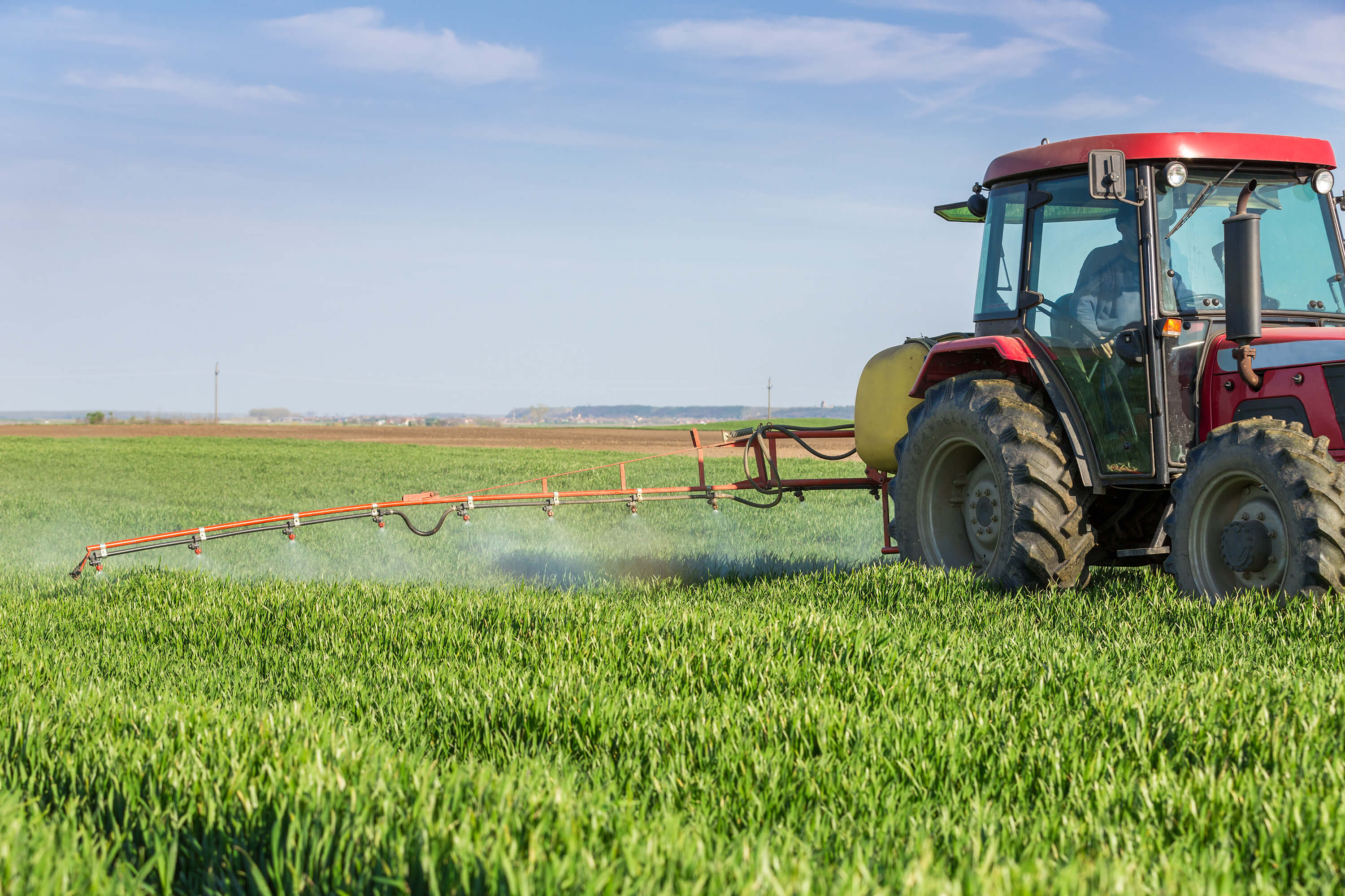 Tractor boom spraying farmland